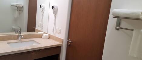 A bathroom with a sink, mirror, towel rack, and two hair dryers.