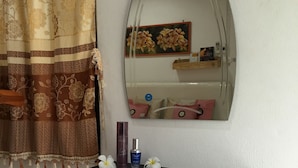 A bathroom with a mirror, a shelf with toiletries, a towel, and a decorative pillow. - Pakasan Garden Home (Khon San)