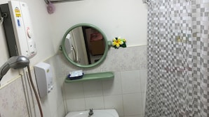 A bathroom with a shower, a sink, a mirror, and a toilet. - Pakasan Garden Home (Khon San)