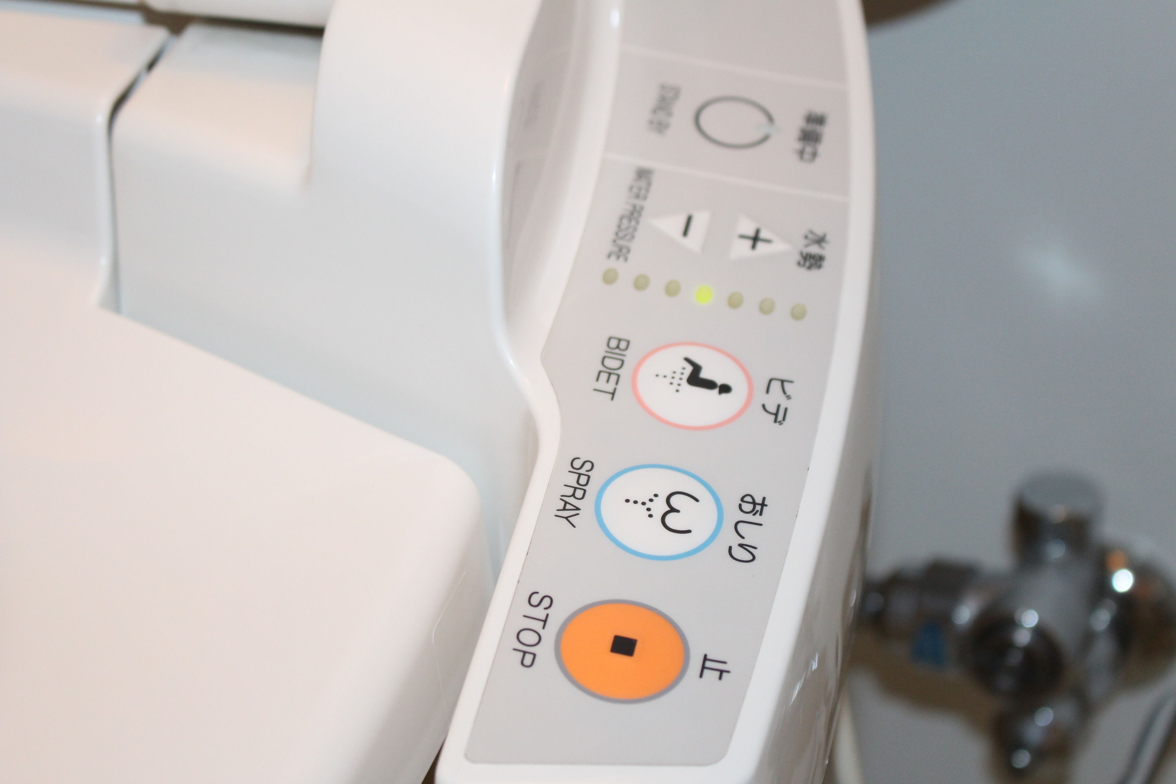 Een bedieningspaneel met knoppen met de tekst 'BIDET', 'SPRAY', 'STOP' en 'OPEN'.
