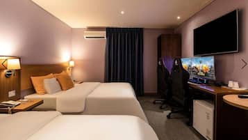 Une chambre d’hôtel avec deux lits, un bureau avec un ordinateur, une télévision et un appareil de climatisation.