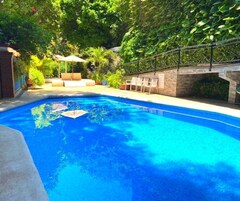 Una piscina al aire libre, sombrillas, sillones reclinables de piscina