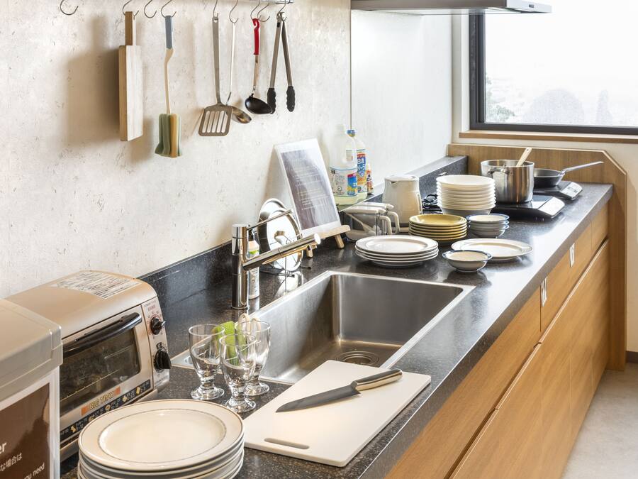 A kitchen with a stainless steel sink, a toaster, and various dishes and utensils.