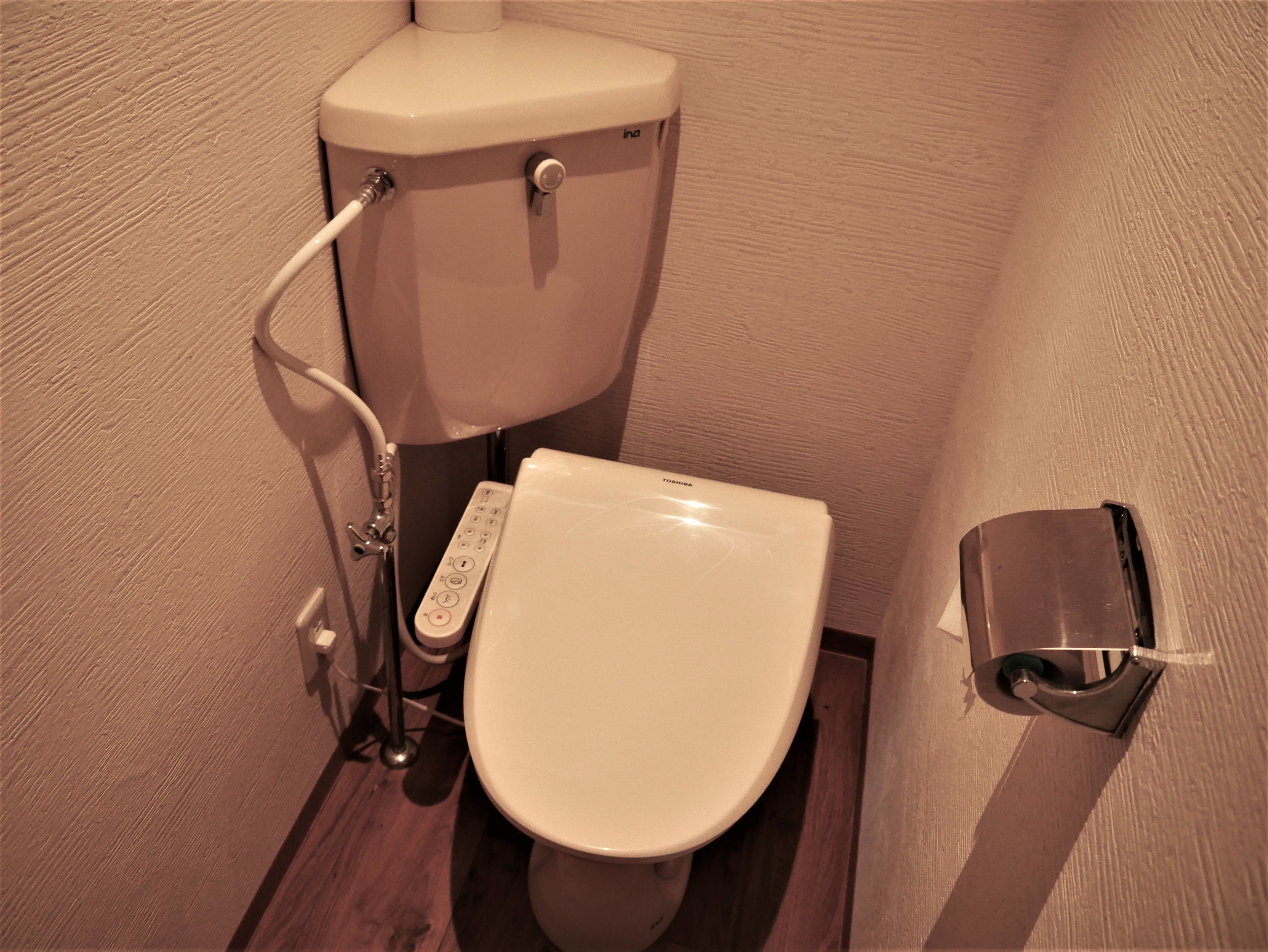 A toilet with a control panel and a bidet attachment.