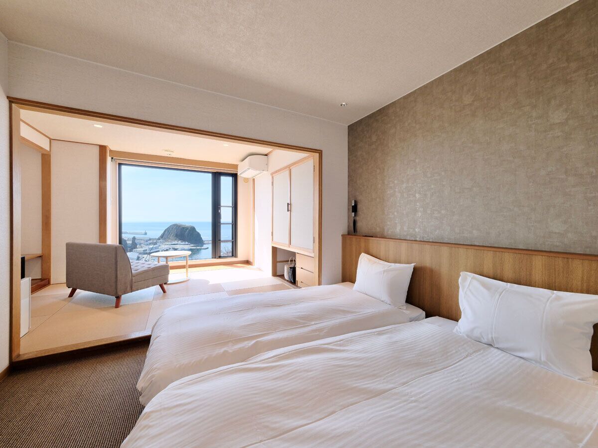 Habitación de hotel con una cama grande, una silla y vista al mar.