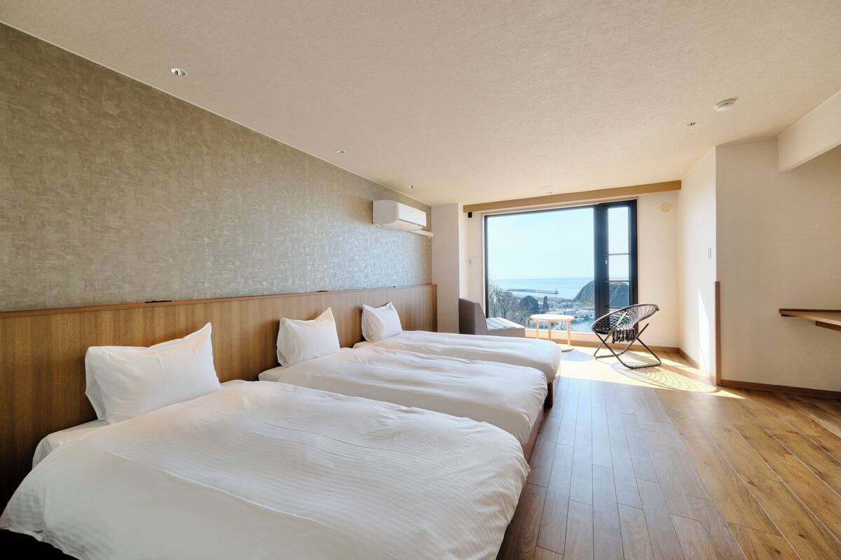 A hotel room with two beds, a large window, and a view of the city.