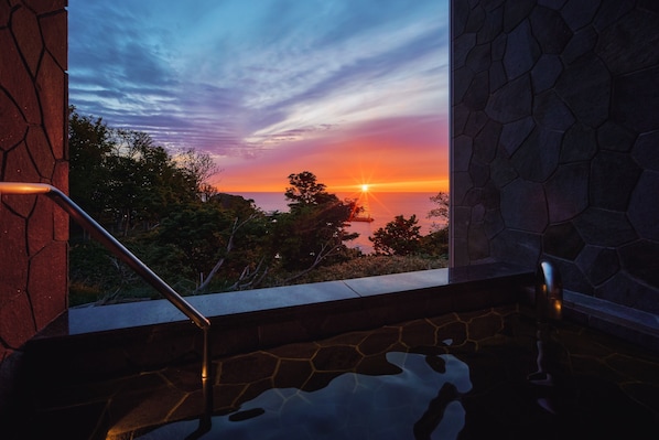 Vista del atardecer desde un balcón de piedra con barandilla metálica.