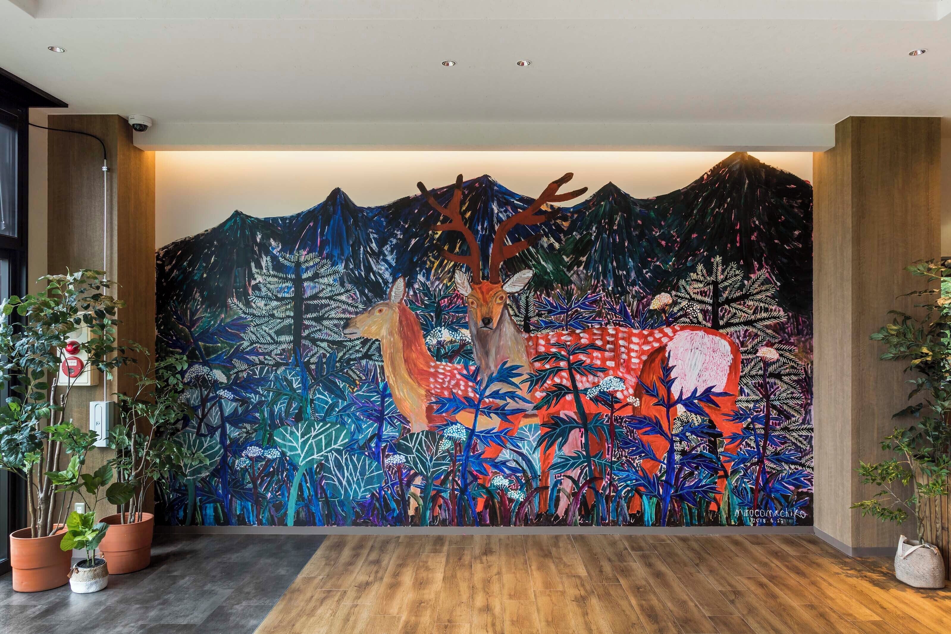 A mural with a deer and forest scene on a wall.