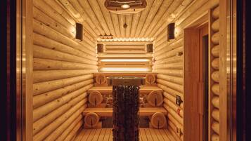 A sauna with wooden walls and benches, a central heating element, and a door on the right.