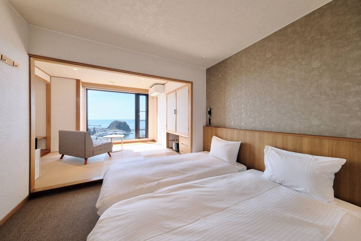 A hotel room with a large bed, a chair, and a view of the ocean.