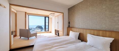 A hotel room with a large bed, a chair, and a view of the sea.