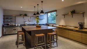 Una cocina moderna con una isla central, taburetes de bar y electrodomésticos integrados.