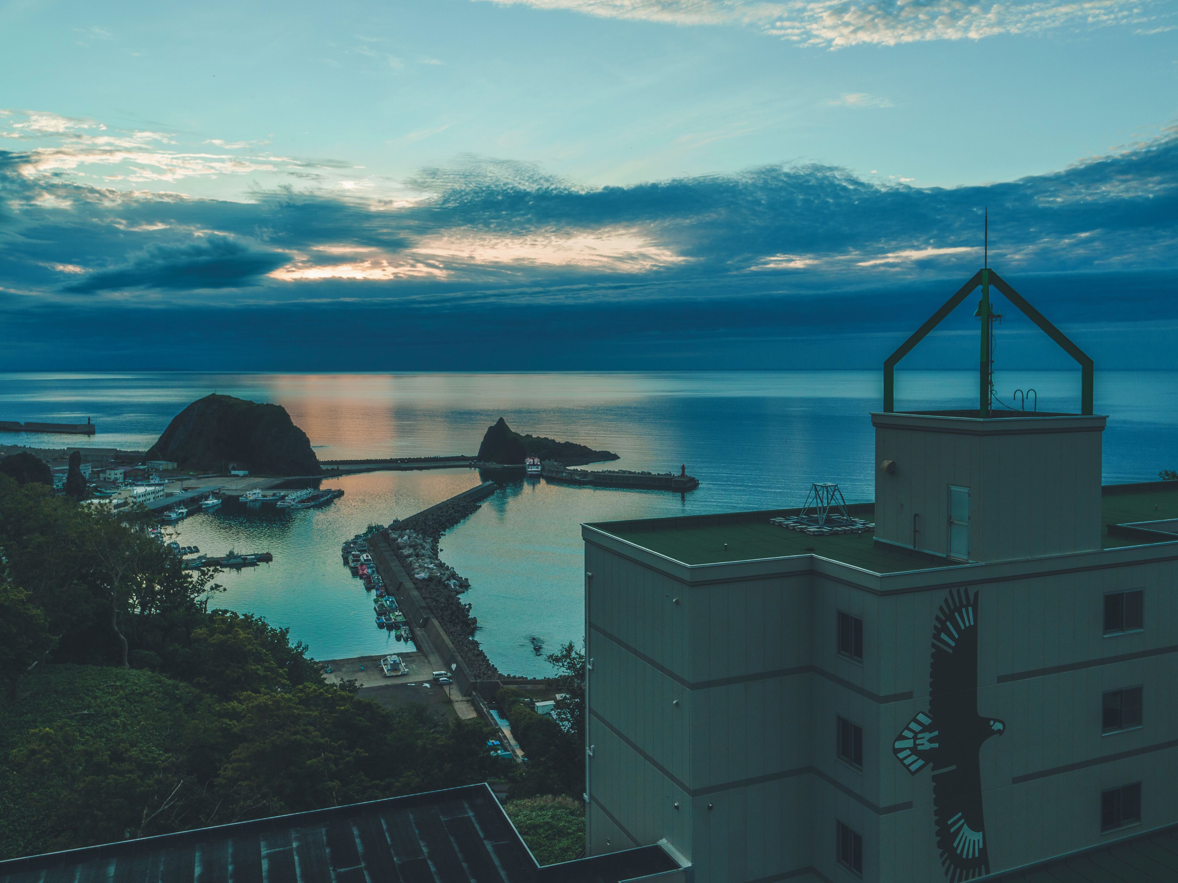 Une vue sur la côte, avec un phare, une mer calme et une jetée qui s’avance dans l’eau.
