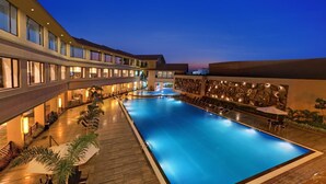Un hôtel doté d’une grande piscine intérieure, de nombreux balcons et d’une façade bien éclairée.