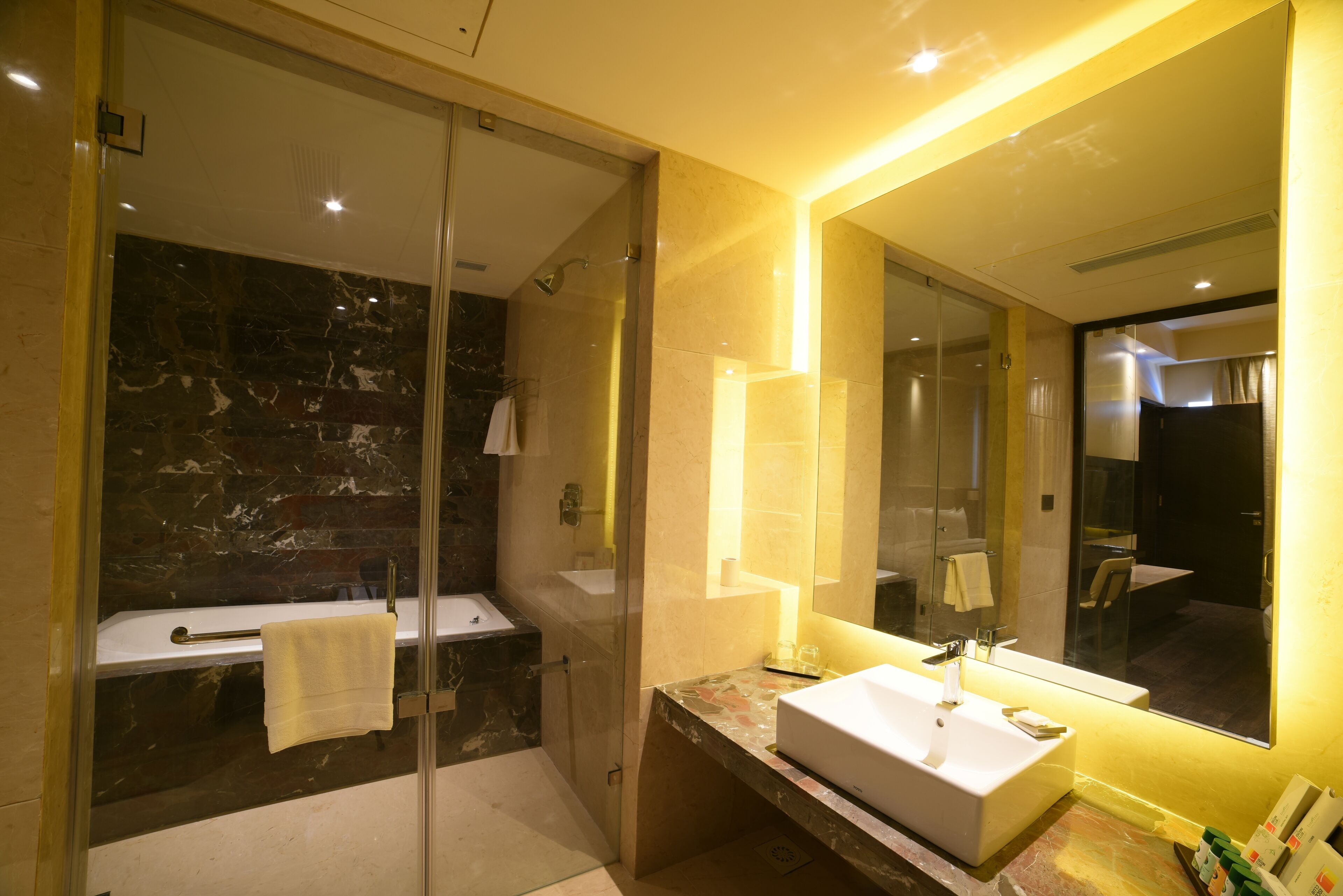 A modern bathroom with a glass-enclosed shower, a white sink, and a large mirror.