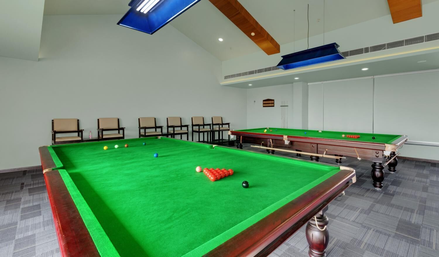Une table de billard avec des billes, des chaises et un téléviseur.