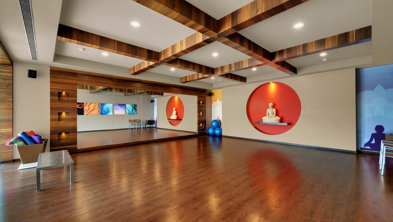 A spacious room with wooden flooring, a large mirror, and a red circular wall decoration.
