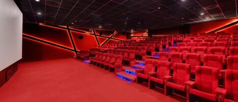 A theater with red seats, a red carpet, and a grid-patterned ceiling.