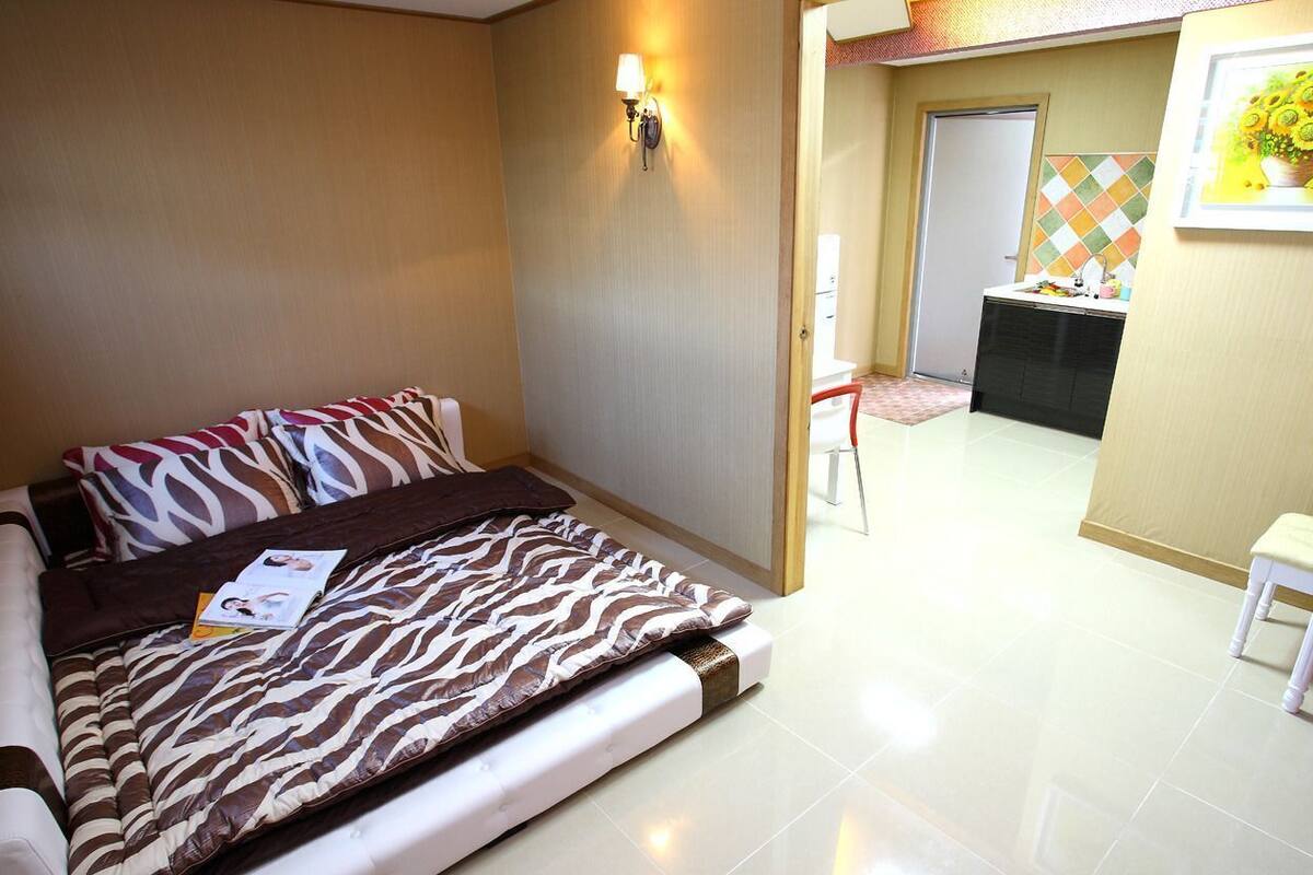 Une chambre d’hôtel avec un lit, un bureau, une chaise, une porte et un tableau au mur.