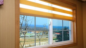 A window with a view of a road, buildings, and a fence. - Bluesean Pension (Namhae)