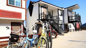 A row of bicycles parked in front of a building with a white facade and black trim. - Bluesean Pension (Namhae)