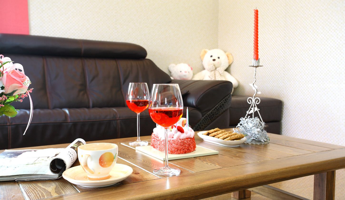 A cozy living room with a brown leather sofa, a wooden coffee table, a teddy bear, a cake, and a candle.