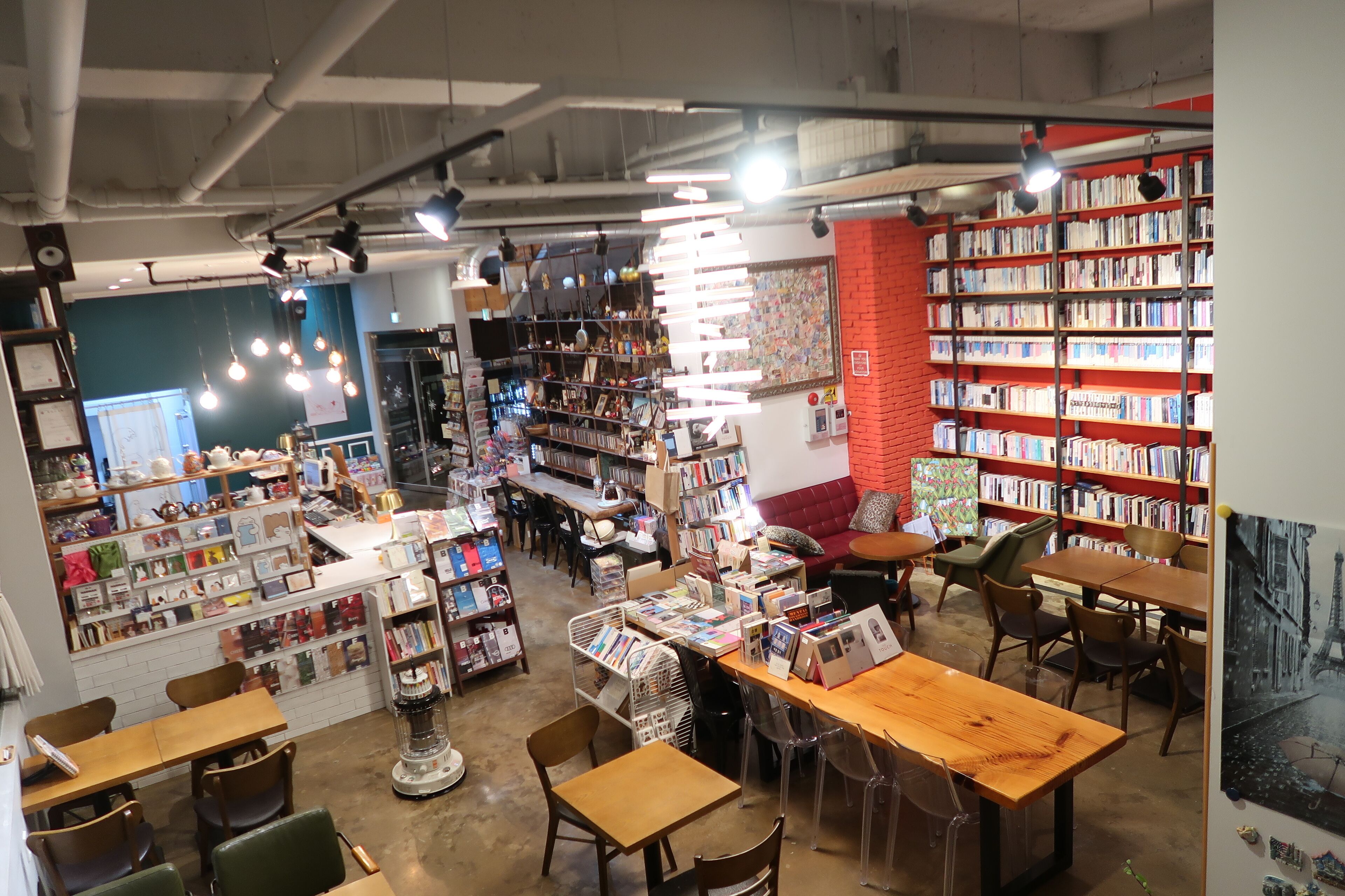 Een boekwinkel met houten tafels en stoelen, boekenkasten en een ruim aanbod aan boeken en tijdschriften.
