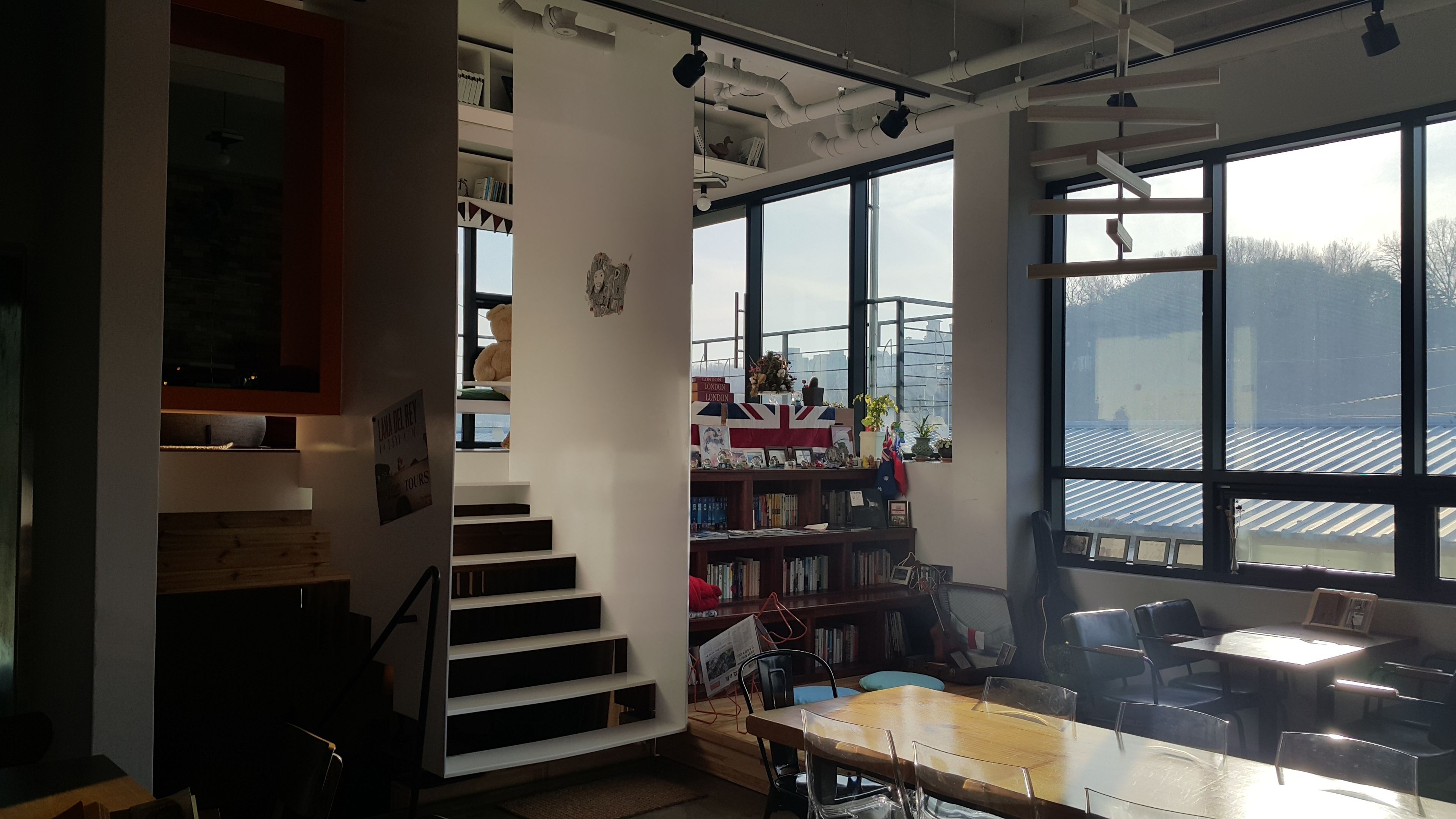Ein moderner Arbeitsraum mit einer Treppe, Bücherregalen und einem großen Fenster mit Blick auf die Stadtlandschaft.