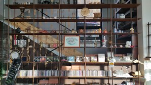 Een meerlaagse boekenkast met verschillende items, waaronder boeken, beeldjes en decoratieve objecten.
