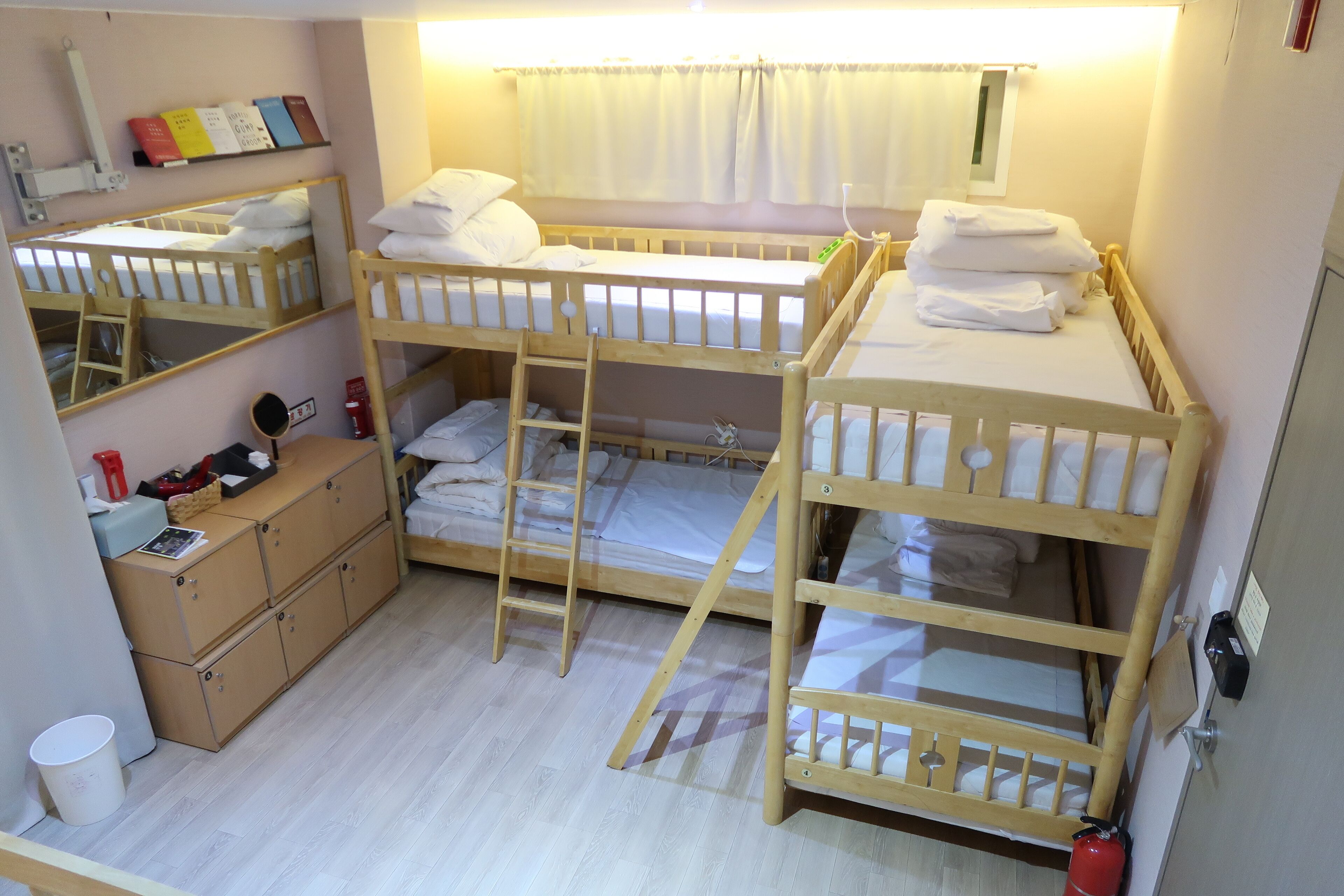 A room with bunk beds, a small desk, a chair, a cabinet, and a mirror.