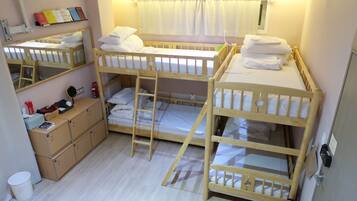 A room with bunk beds, a small desk, a chair, a cabinet, and a mirror.