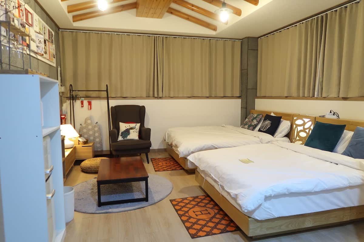A bedroom with two beds, a desk, a chair, and a wardrobe.