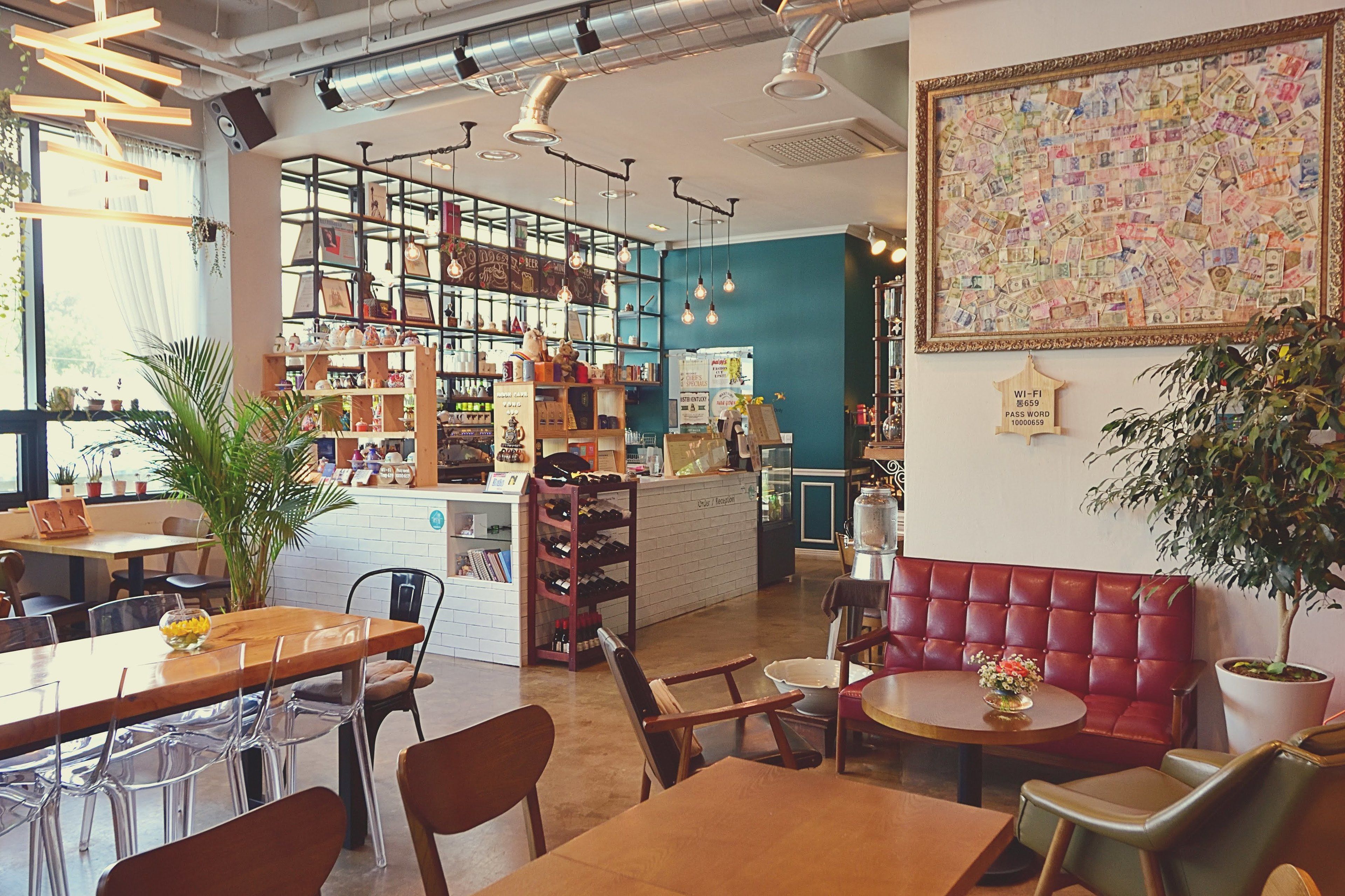A café with a wooden table, chairs, a red cushioned bench, and a wall decorated with currency notes.