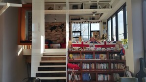 Een trap die leidt naar een hoger gelegen leeshoek met een boekenkast en een groot teddybeer.