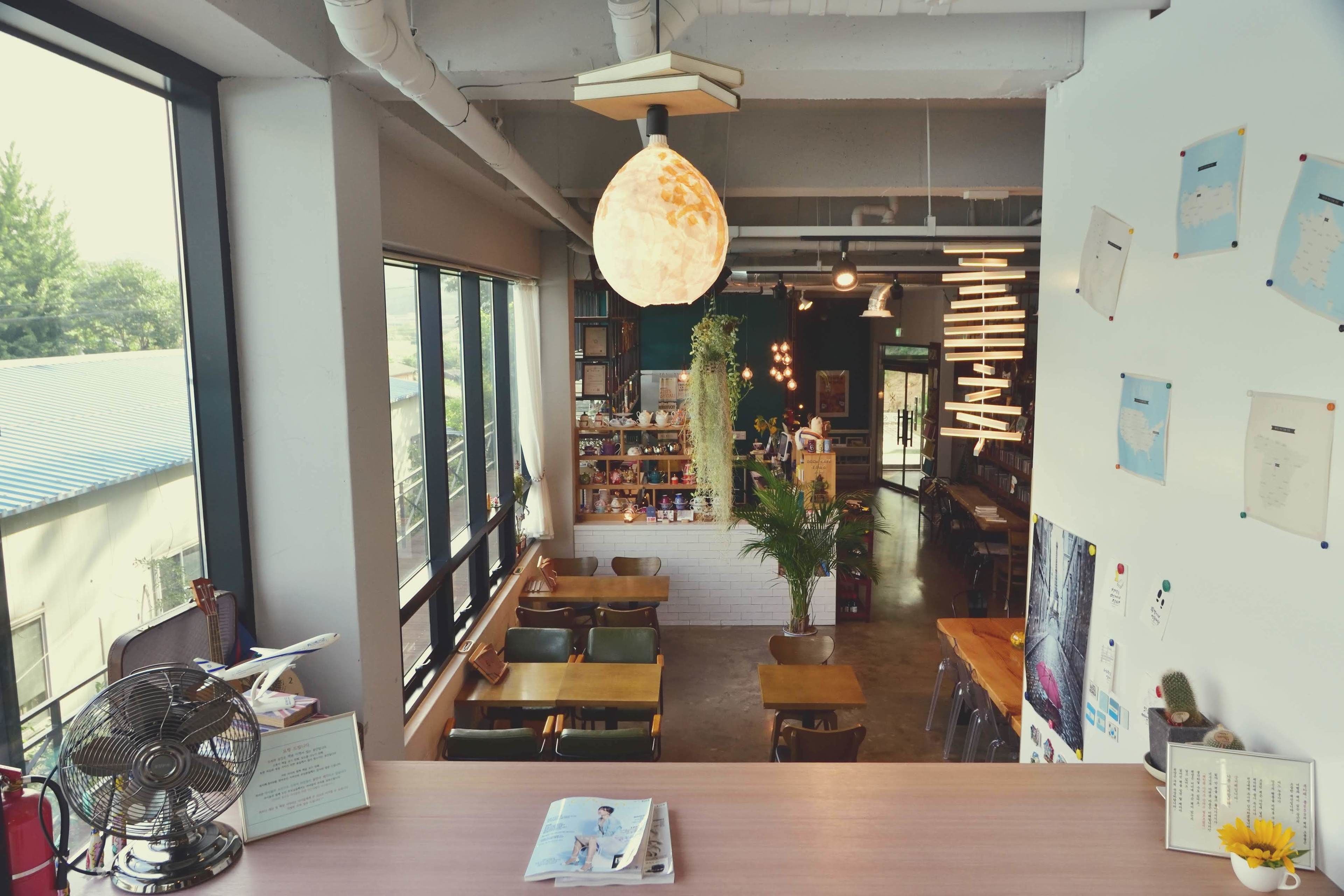 Un café con mostrador de madera, zona de asientos y amplios ventanales.
