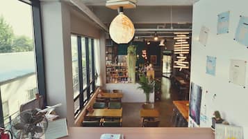Un café con mostrador de madera, zona de asientos y amplios ventanales.