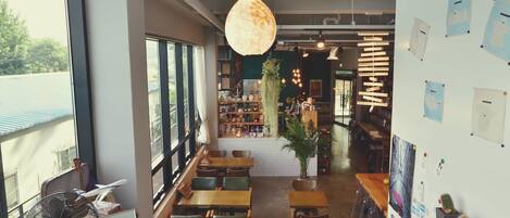 Un café con mostrador de madera, zona de asientos y amplios ventanales.