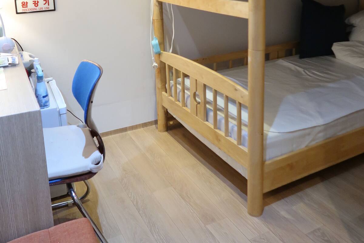 A bunk bed room with a desk, chair, and a bookshelf.