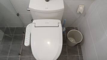 Des toilettes modernes dotées d’un panneau de commande, d’un accessoire de type bidet et d’une brosse pour les toilettes.