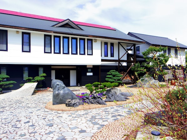 A modern building with a tiled courtyard, stone sculptures, and well-maintained greenery.