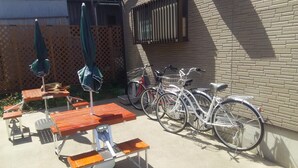 A patio area with picnic tables and umbrellas, a brick wall, and bicycles parked against it. - J's BackPackers Guest House - Hostel (Tokyo)