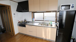 A kitchen with a dishwasher, sink, stove, microwave, and refrigerator. - J's BackPackers Guest House - Hostel (Tokyo)
