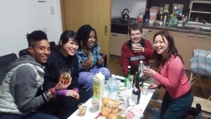 A group of people sitting around a table with various food items and drinks. - J's BackPackers Guest House - Hostel (Tokyo)