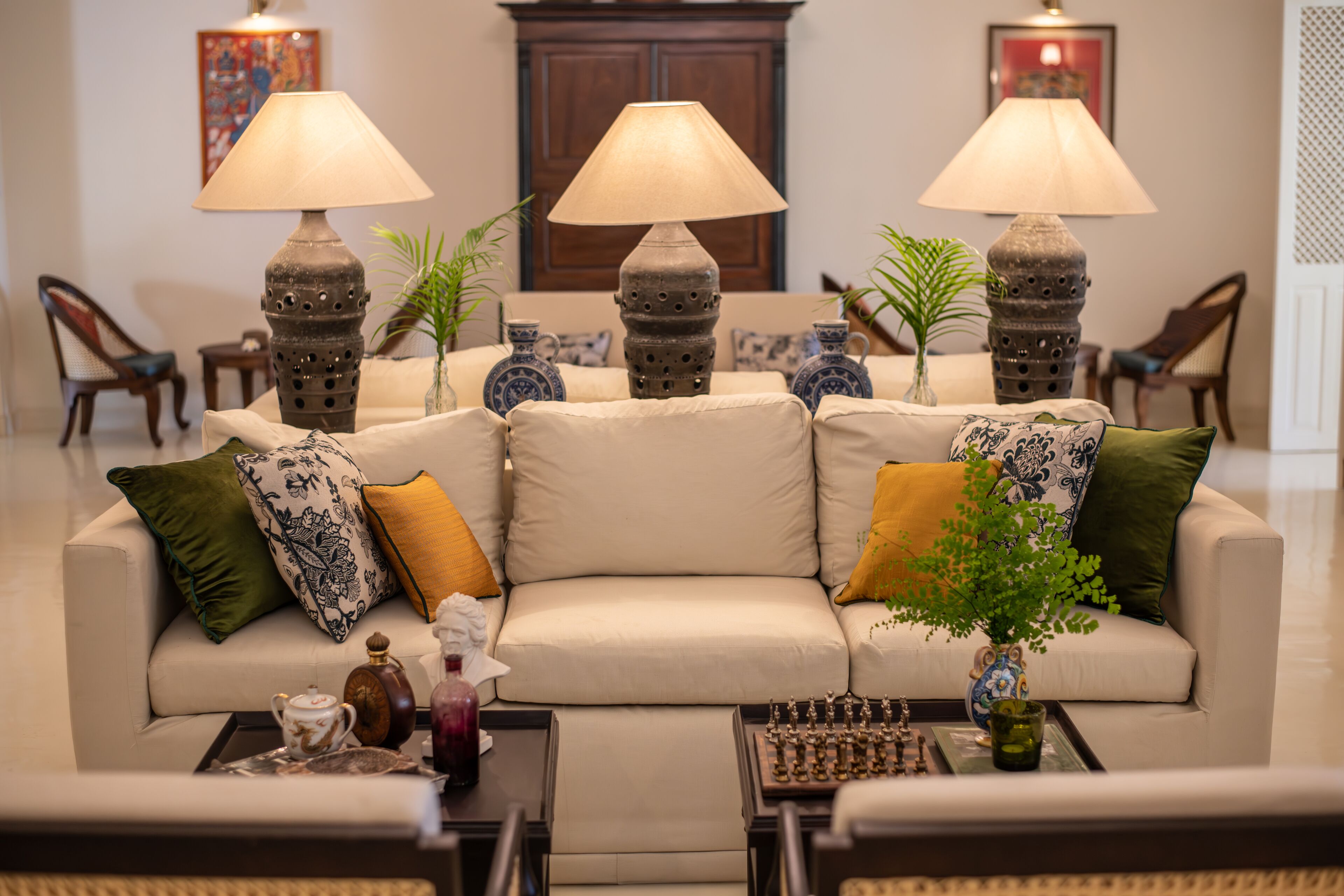 Un salón bien amueblado con sofá, dos lámparas, un tablero de ajedrez y elementos decorativos.