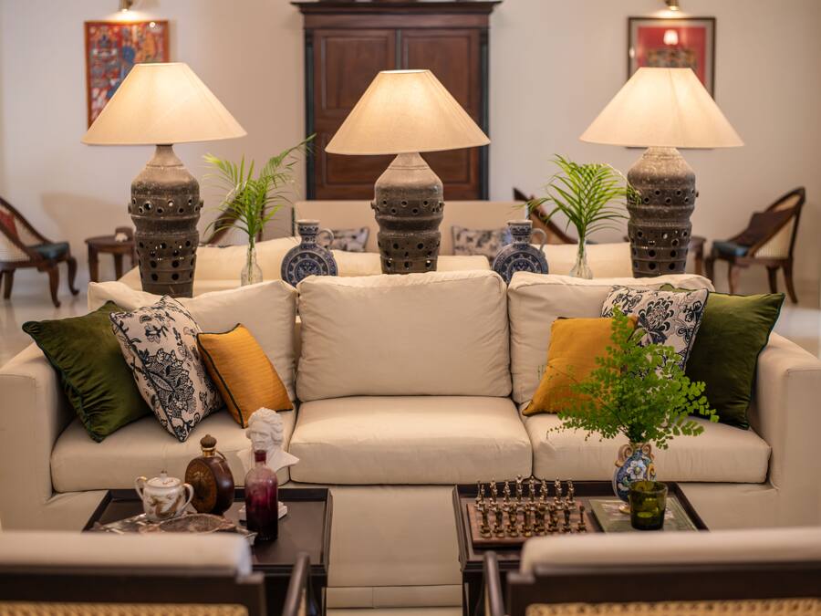 Un salón bien amueblado con sofá, dos lámparas, un tablero de ajedrez y elementos decorativos.