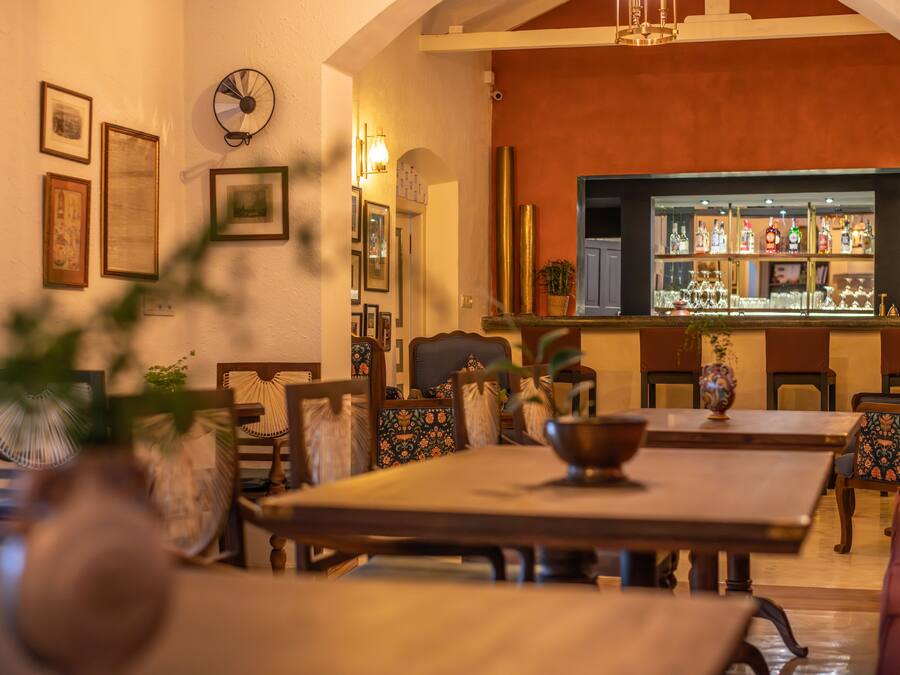 A dining area with a long table, chairs, and a bar in the background.