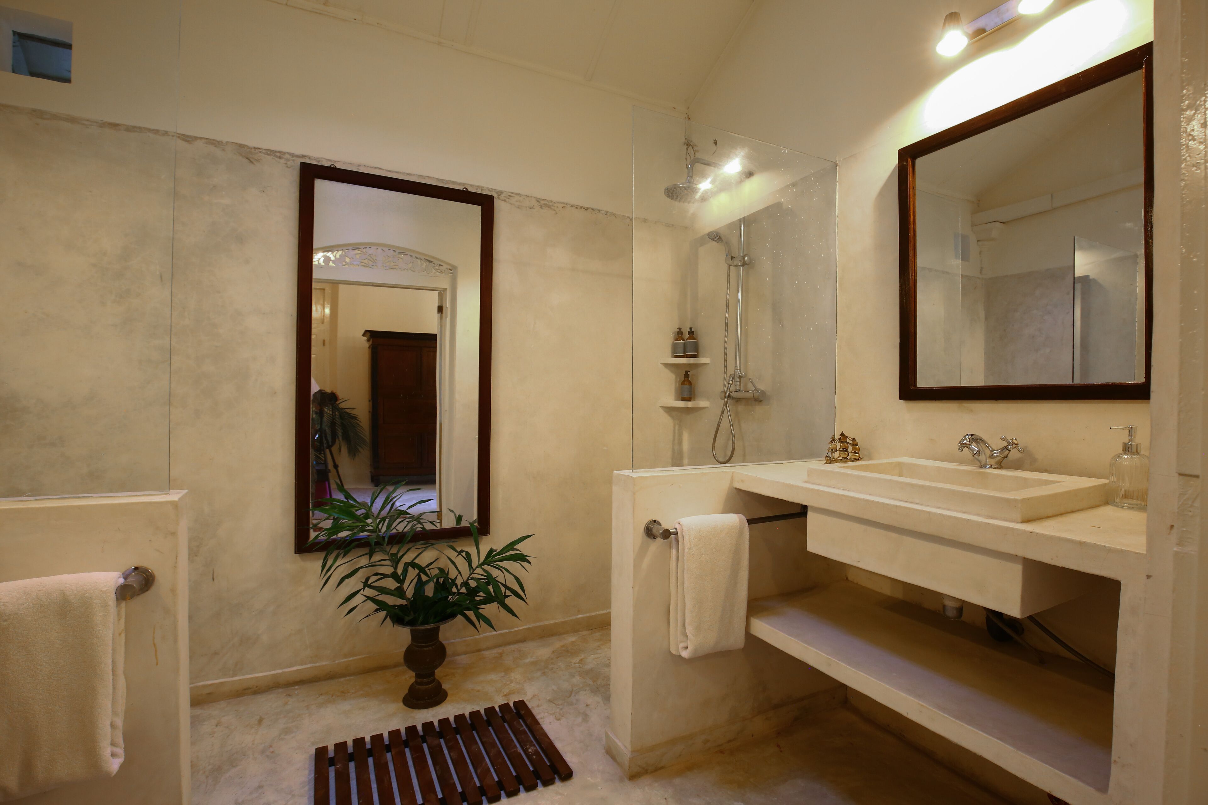 A bathroom with a large mirror, a sink, and a shower.