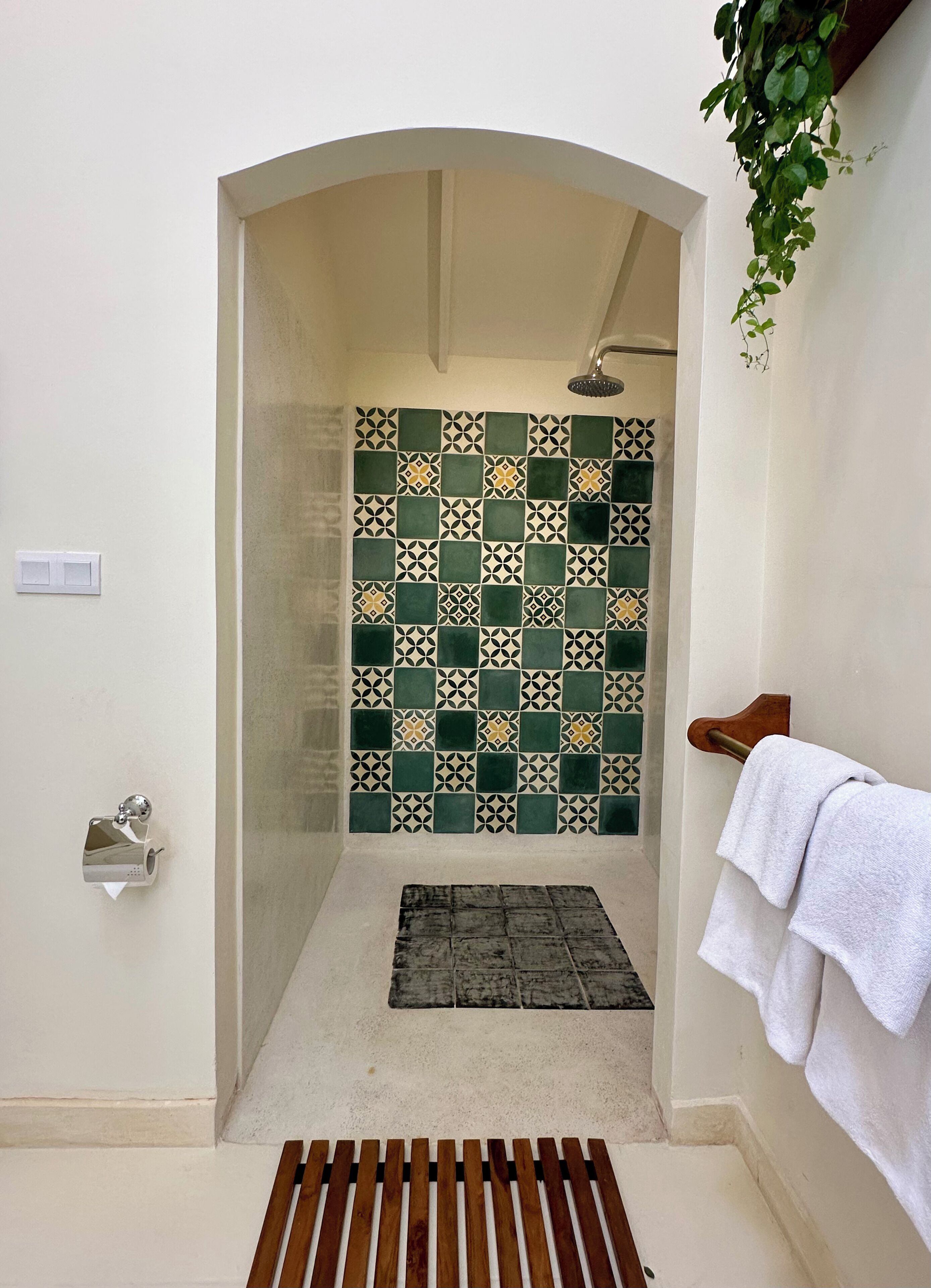 A shower area with a tiled wall, a wooden bench, and a towel rack.