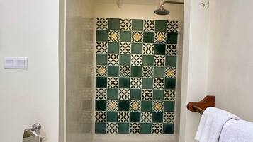 A shower area with a tiled wall, a wooden bench, and a towel rack.