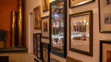 A wall with multiple framed photographs and a potted plant.